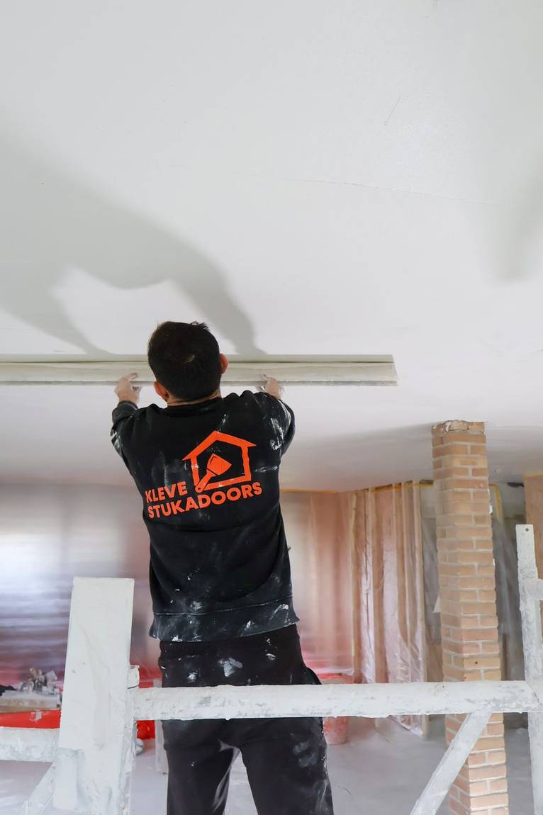 Vakman van Kleve Stukadoors werkt een plafond af